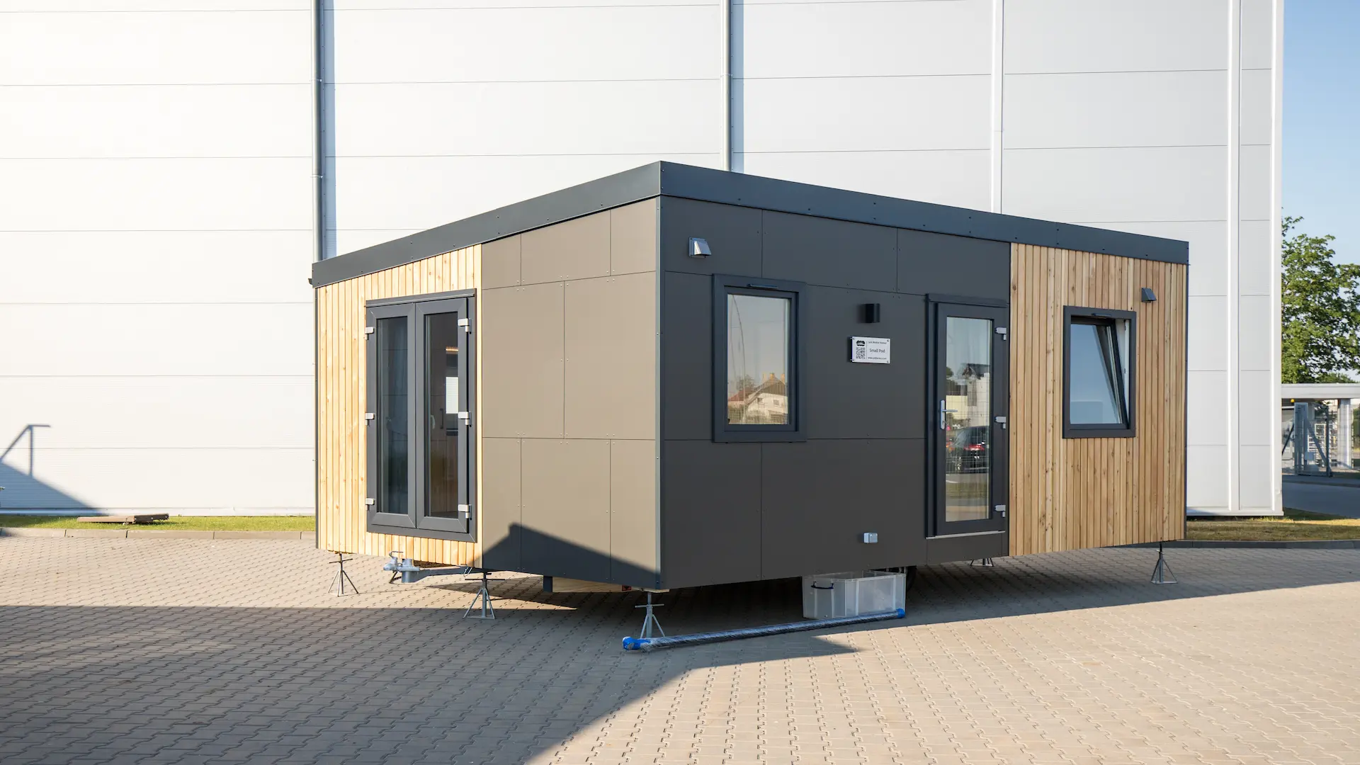 TwinPod mobile home on the territory of the factory, one part of the covering made of anthracite metal sheets, the other of Siberian wood.