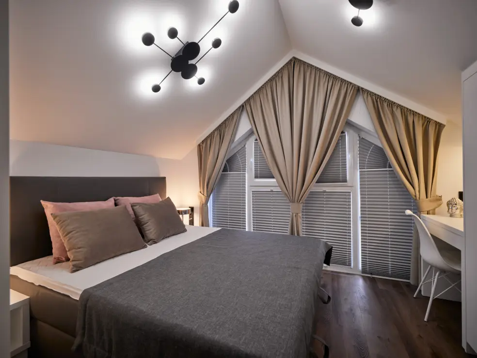 Bed and designer light fixture on the ceiling in the bedroom of Sunrise House